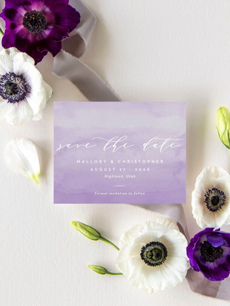 watercolored lilac and white wedding save the date with white script lettering surrounded by white and purple anemone flowers