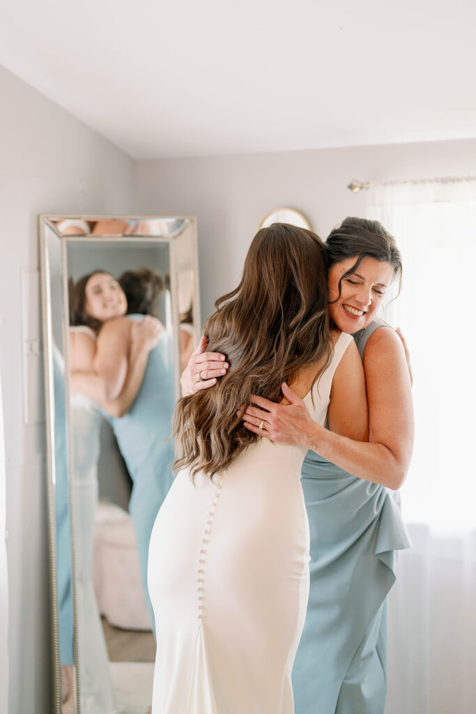 Bride hugging her mother after getting dressed before first look