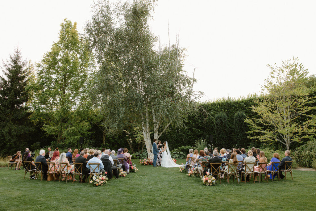 Outdoor wedding ceremony on the lawn surrounded by lush greenery at Briarwood Estate, a beautiful example of garden wedding venues in Washington.