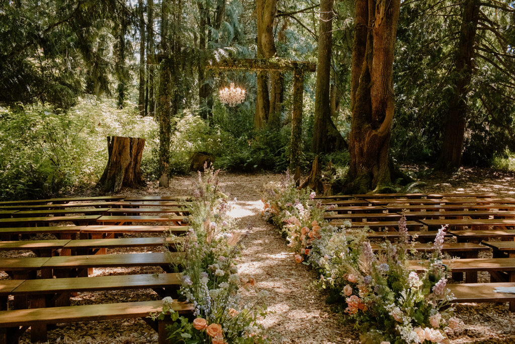 Outdoor woodland ceremony space with wooden benches and floral aisle at Twin Willow Gardens, a breathtaking Pacific Northwest garden wedding venue.