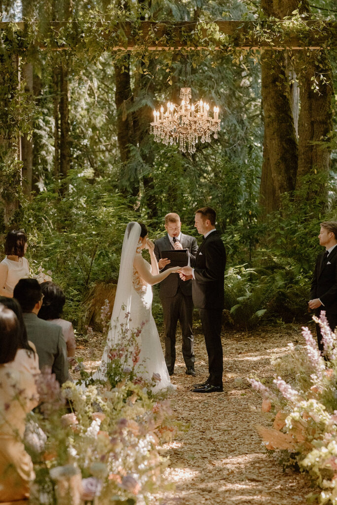 Outdoor forest ceremony at Twin Willow Gardens with chandelier altar and floral aisle, a stunning example of Pacific Northwest garden wedding venues