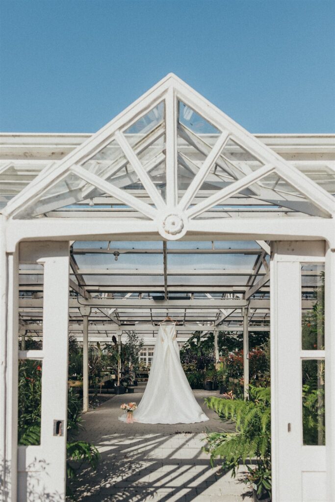 Wedding dress displayed inside the bright greenhouse at Christianson's Nursery, a stunning location among Pacific Northwest garden wedding venues.