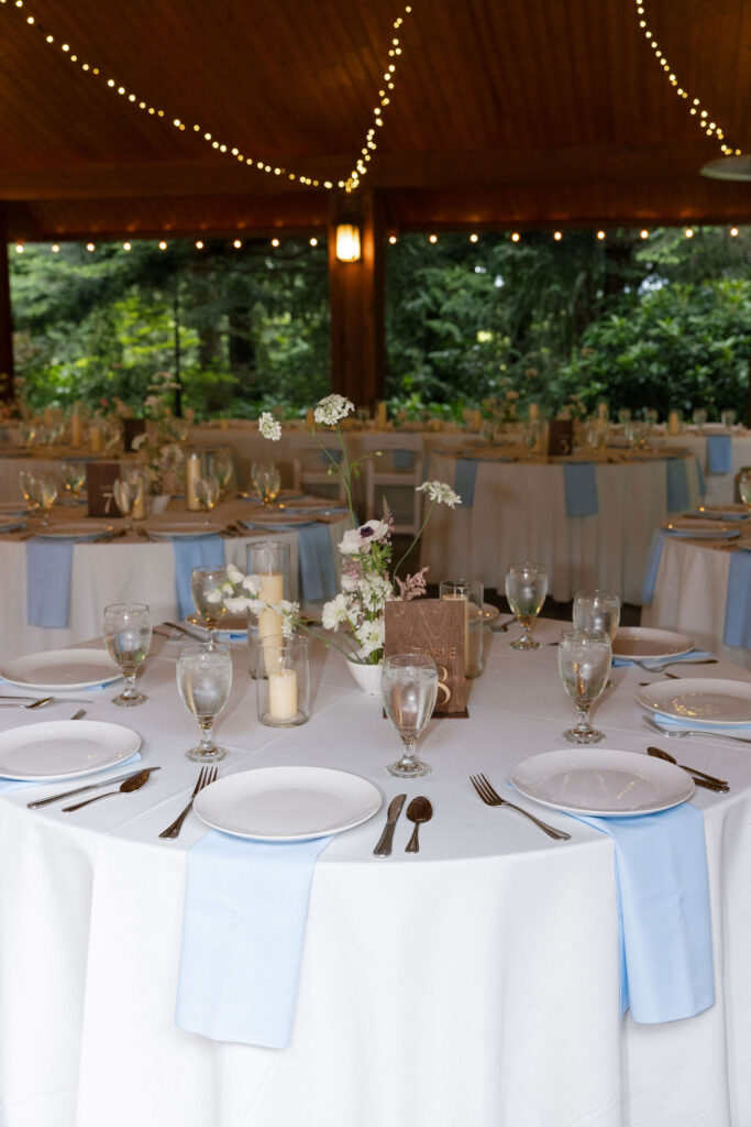 Elegant reception table with soft blue linens and candlelight inside the pavilion at Evergreen Gardens garden wedding venue.