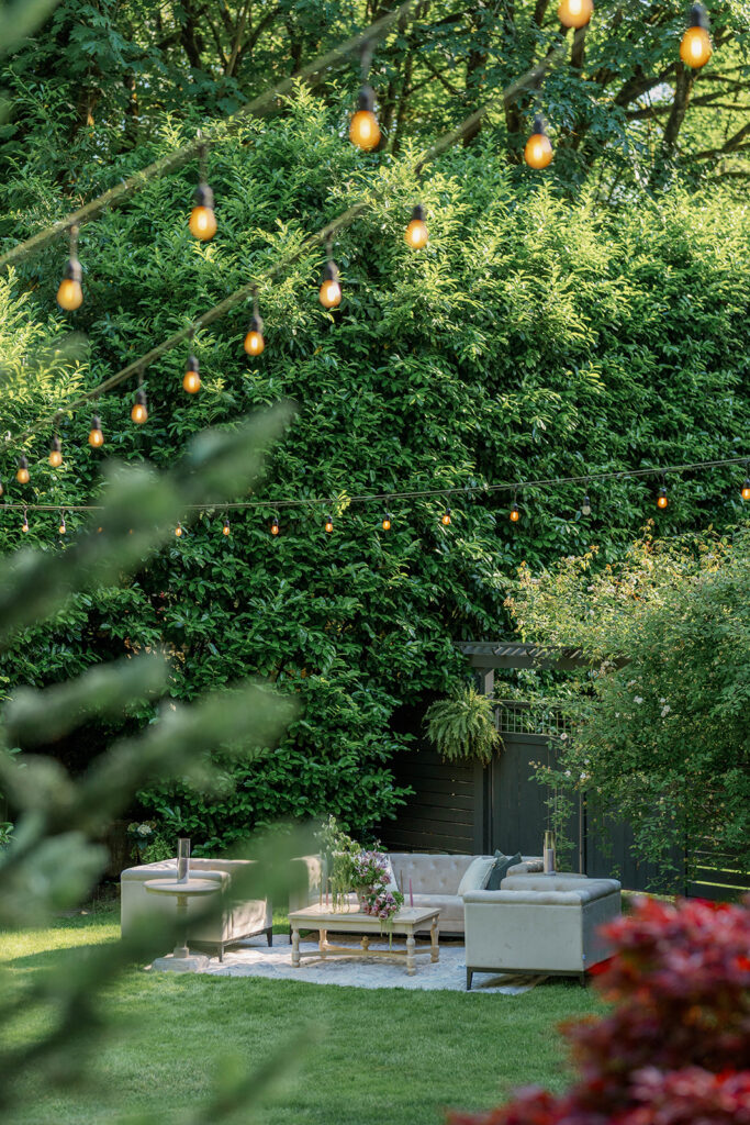Romantic lounge seating under string lights surrounded by greenery at Parties on the Terrace garden wedding venue.