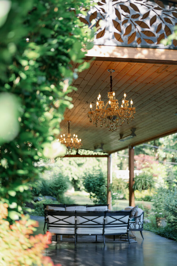 Covered pavilion with chandeliers and ivy-covered beams at Parties on the Terrace, an elegant garden wedding venue in Washington.